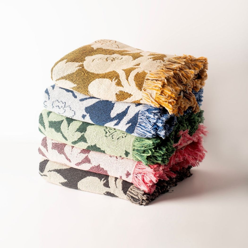 Stack of Addy reversible floral woven throw blankets in five colorways