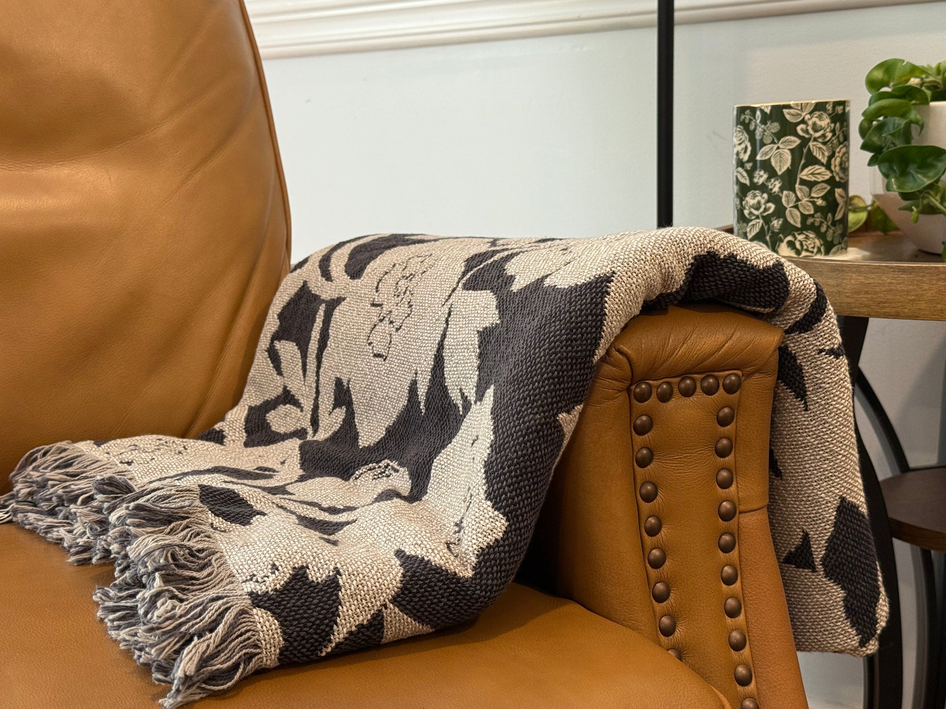 Patterned throw blanket draped over a brown armchair with a blurred indoor setting.
