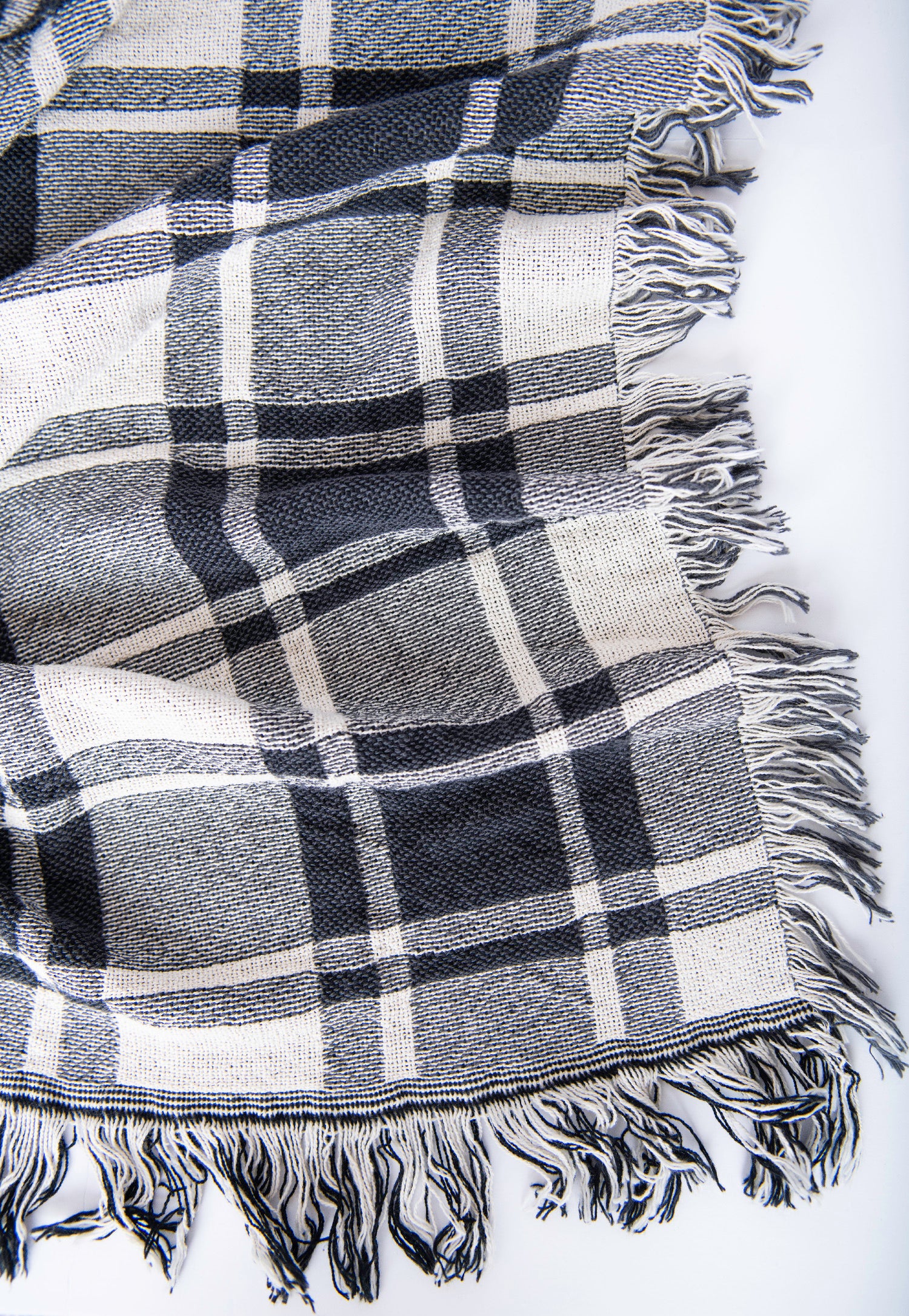 Close-up of Ellis black, gray, and cream plaid woven cotton throw with fringe