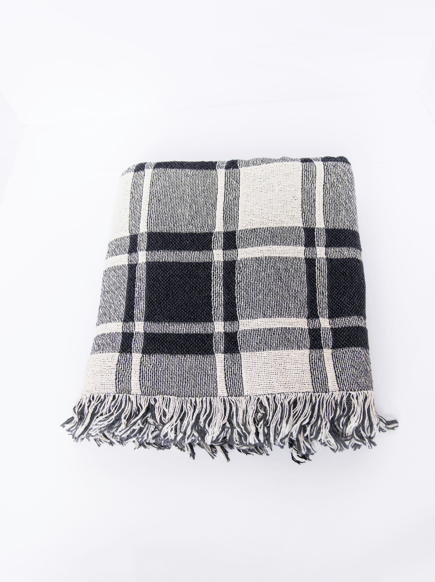 Overhead view of folded Ellis neutral plaid woven throw with fringe