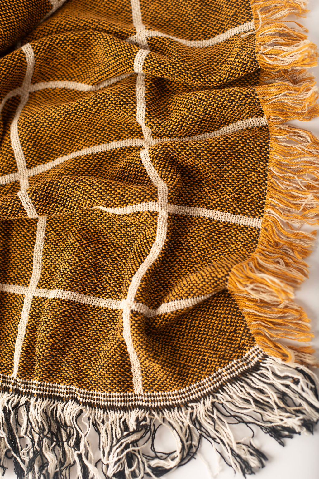 Close-up of Greer Acorn golden brown and cream windowpane grid woven cotton throw with fringe