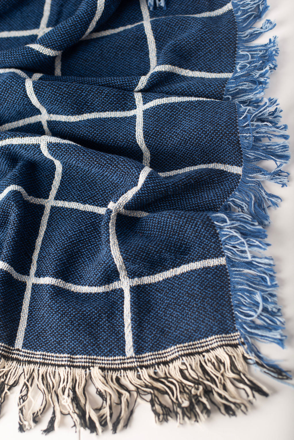 Close-up of Greer Lapis blue and cream windowpane grid woven cotton throw with fringe