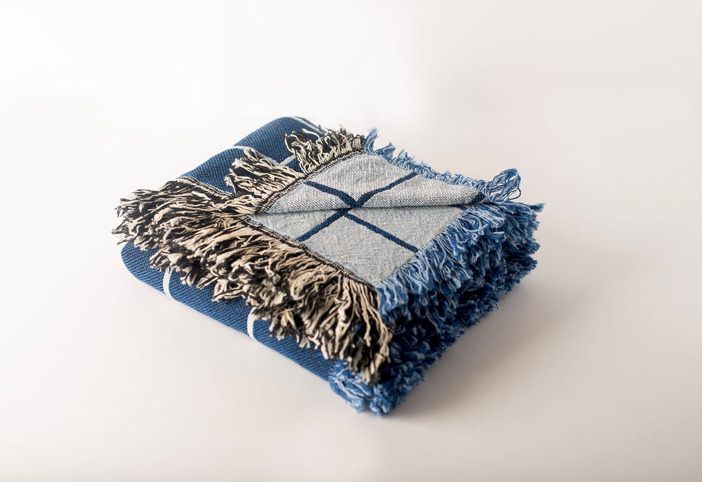 Greer Lapis blue grid throw folded to show its lighter reversible side and contrasting fringe