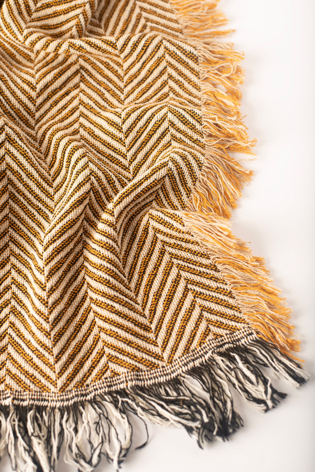 Textured blanket with chevron pattern and fringe on a white background