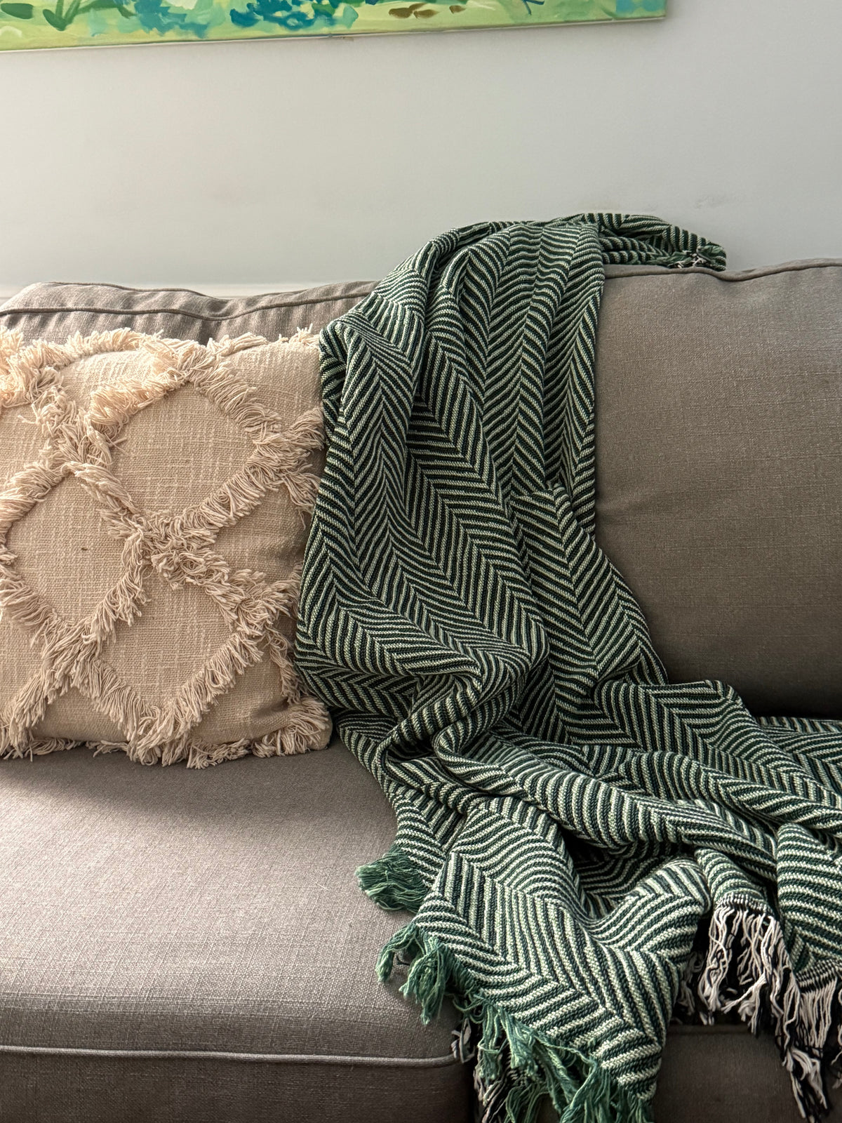 Henry Verbena green herringbone woven cotton throw blanket draped over a neutral sofa