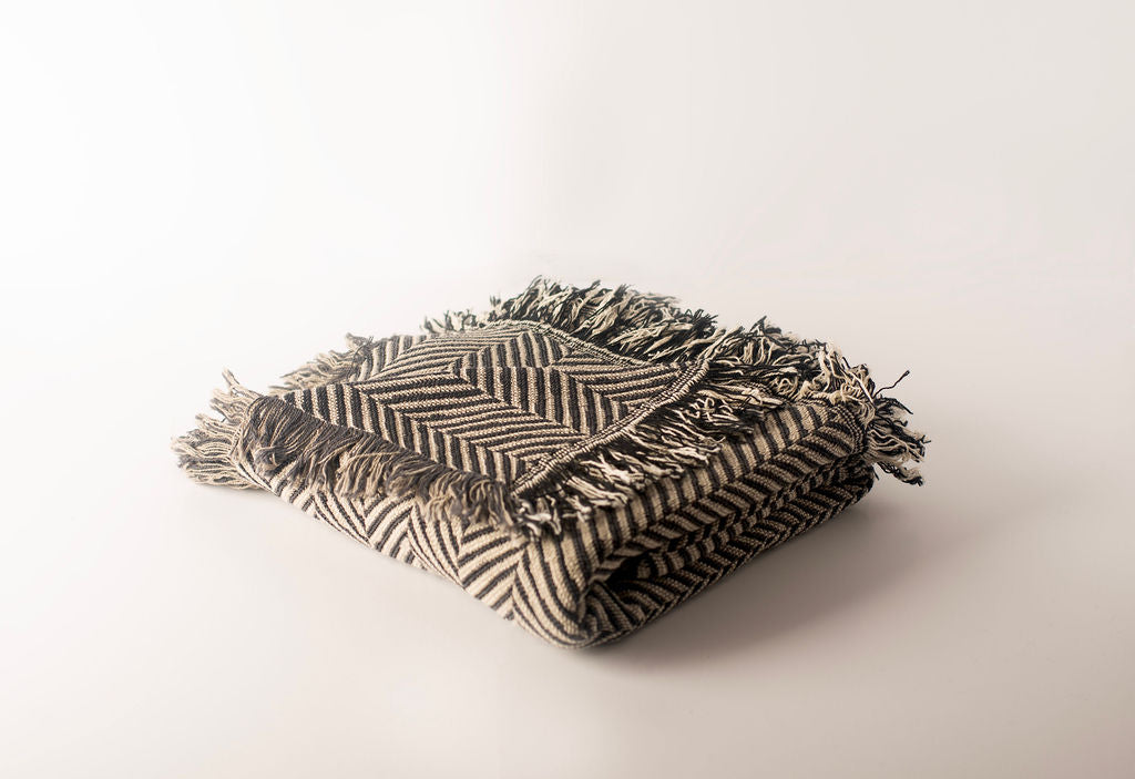 Henry Stone neutral herringbone throw loosely folded to show its reversible woven texture and fringe
