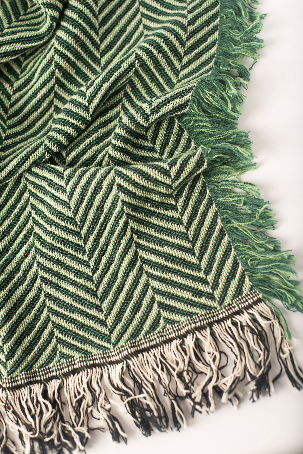 Close-up of Henry Verbena green and cream herringbone woven cotton throw with fringe