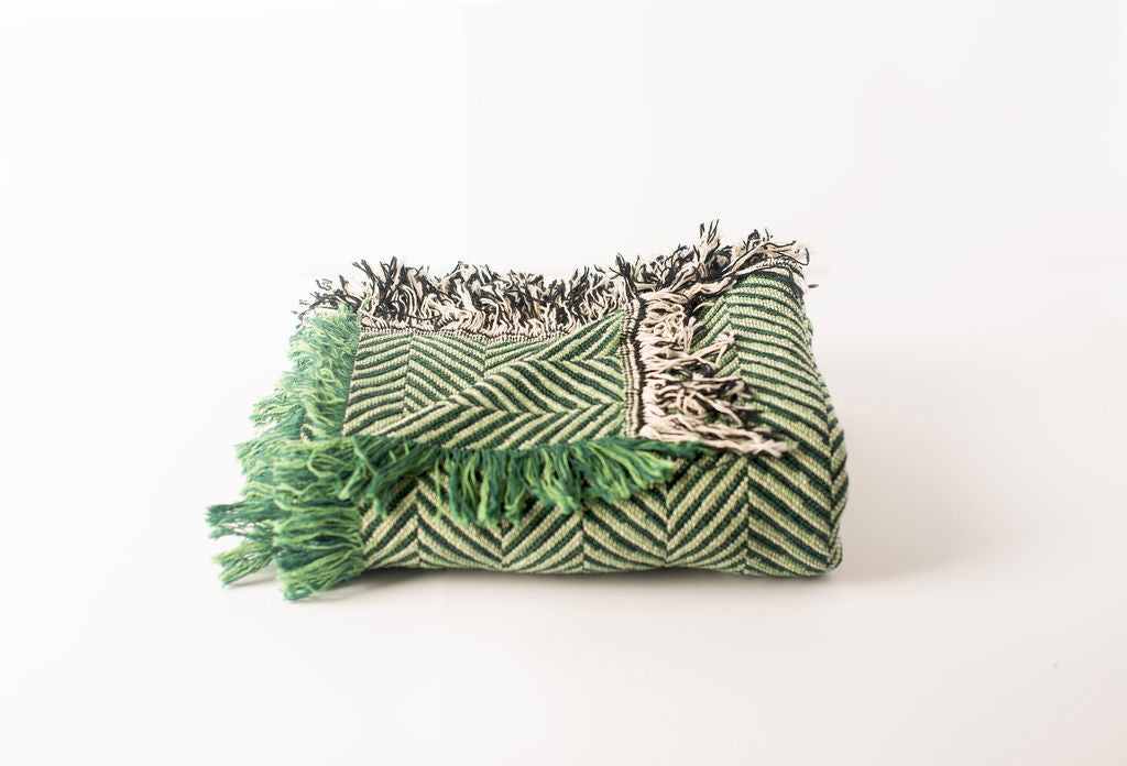 Henry Verbena green herringbone throw loosely folded to show its  reversible woven texture and fringe