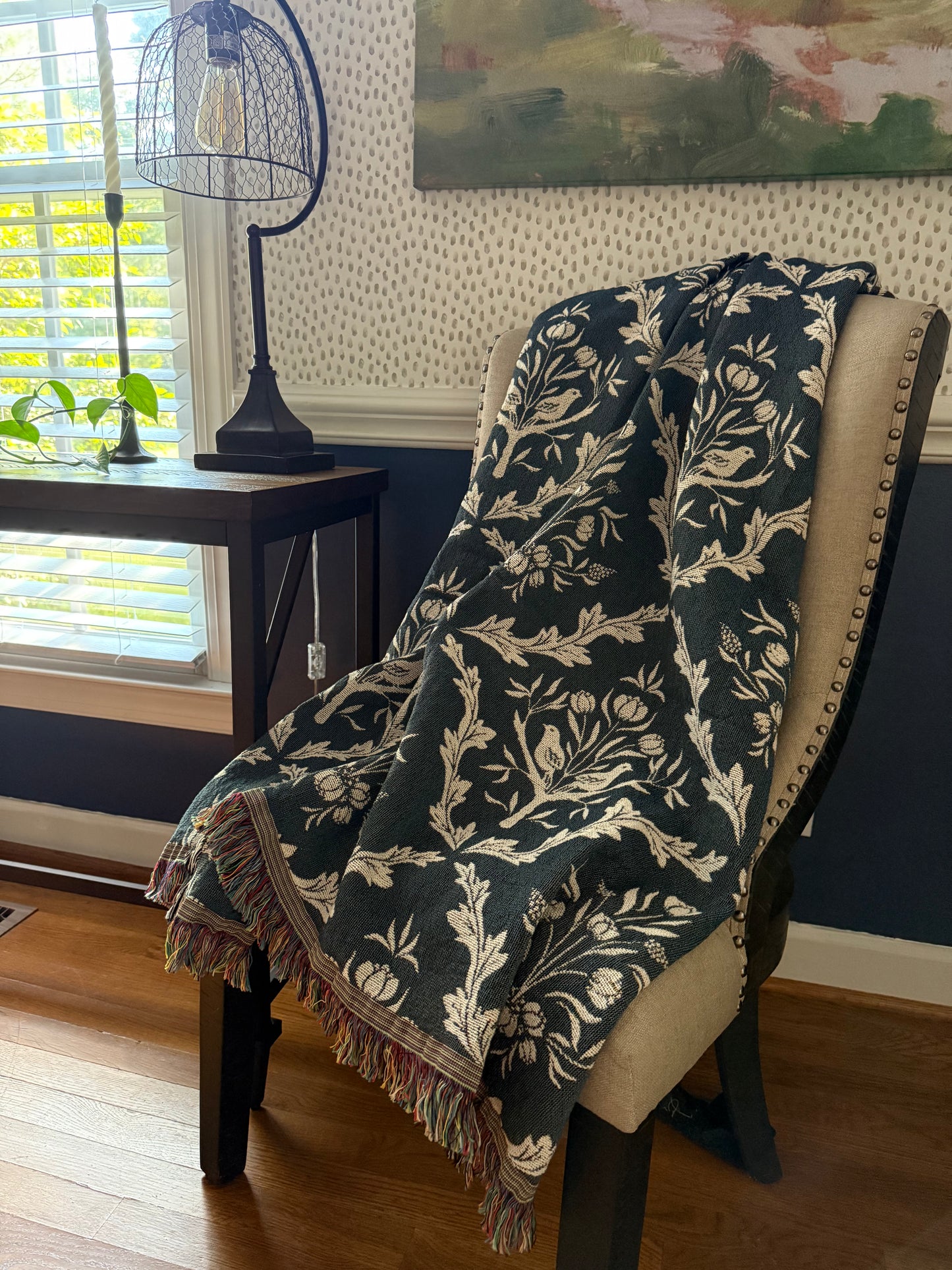 Isobel Thistle botanical throw blanket draped over an upholstered wingback chair in a traditional interior