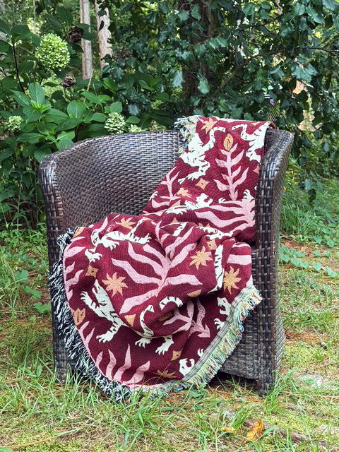 Leona Solstice red tiger throw blanket draped over a wicker chair in a garden