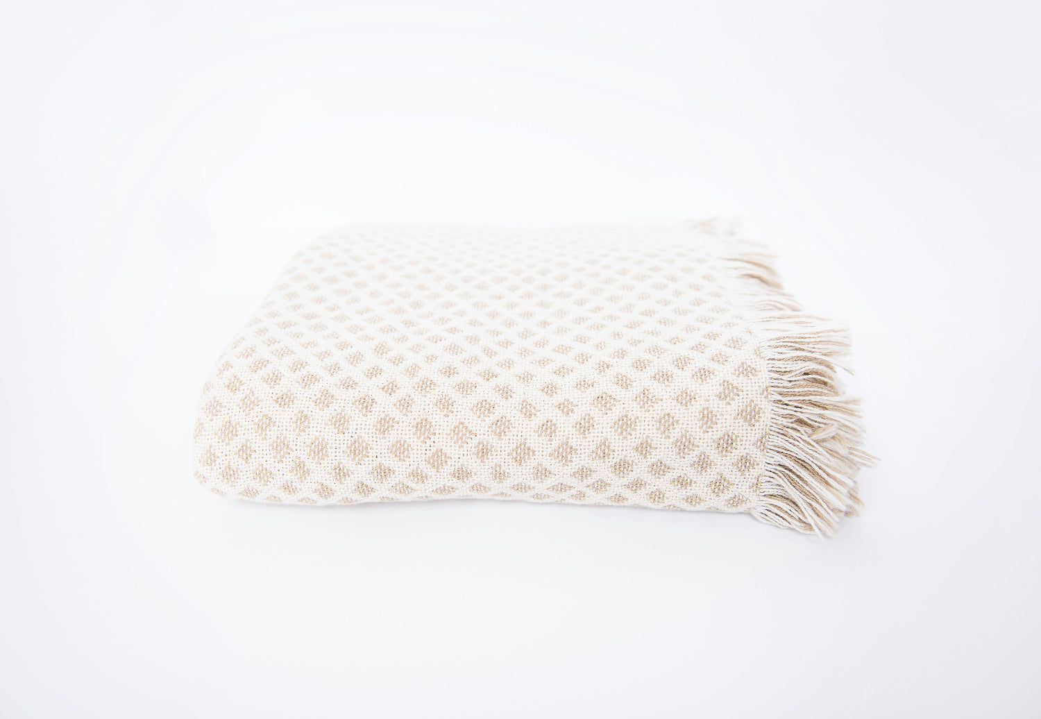 Front view of folded cream and beige diamond woven cotton throw on a white background