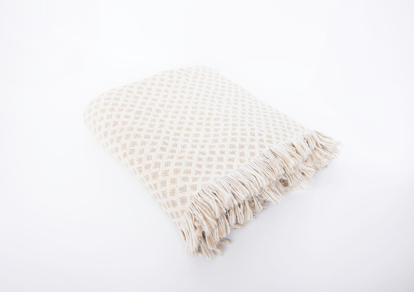 Side view of folded Rowan neutral diamond-patterned woven throw with fringe