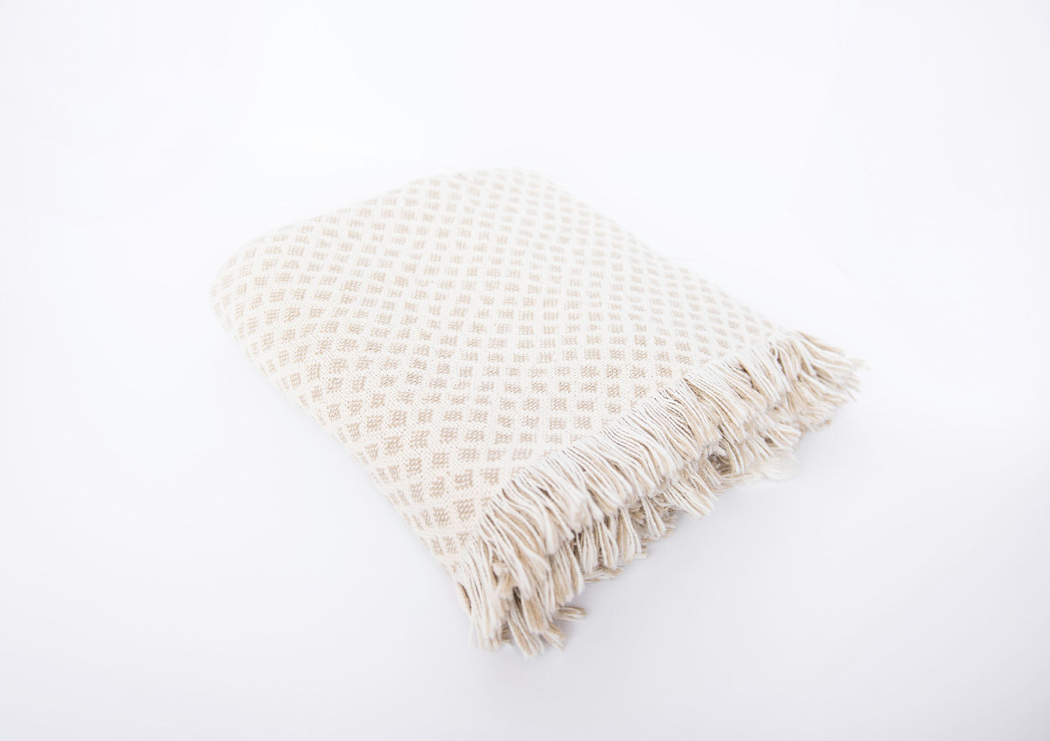 Side view of folded Rowan neutral diamond-patterned woven throw with fringe