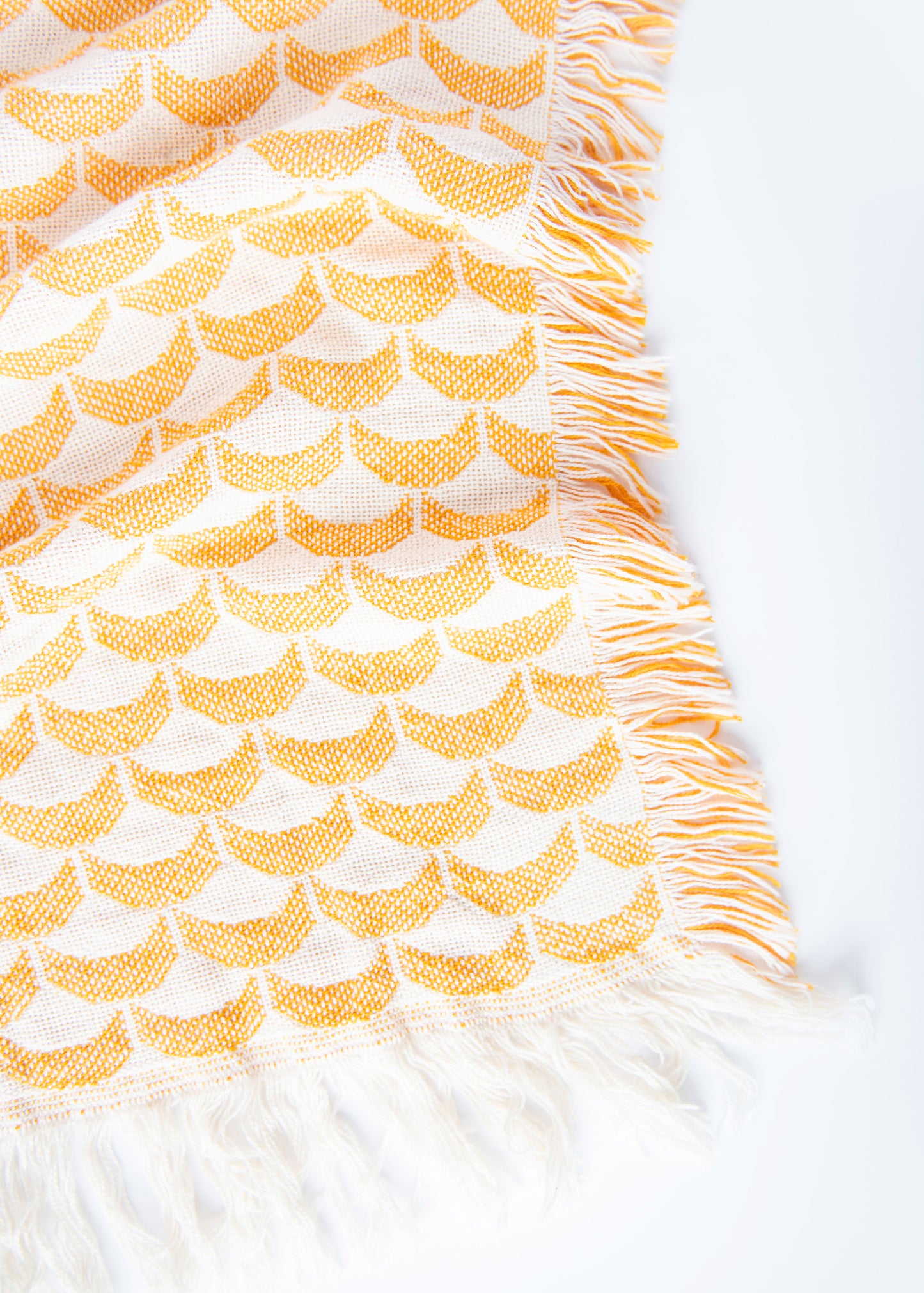 Close-up of Sadie golden yellow and cream scallop woven cotton throw with fringe