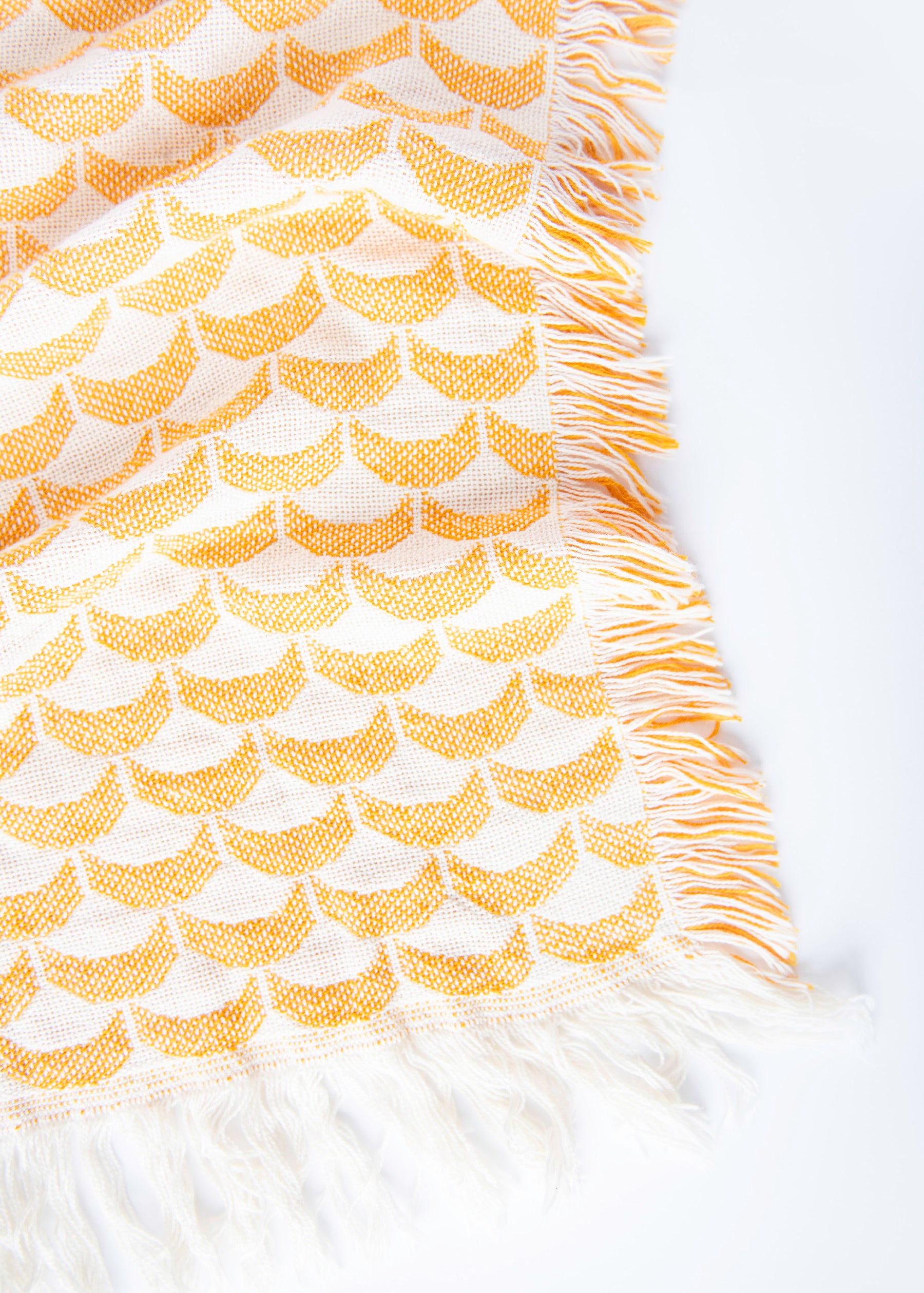 Close-up of Sadie golden yellow and cream scallop woven cotton throw with fringe