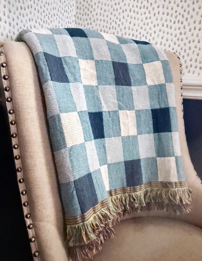 Tilda Bayberry blue check woven cotton throw draped over a traditional upholstered chair